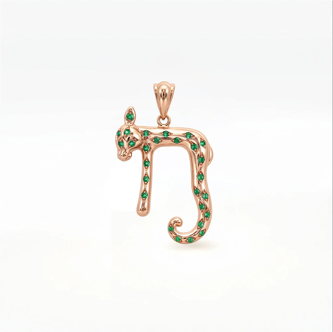 A rose gold pendant shaped like the Hebrew letter Nun, embellished with small green gemstones, shown on a clean white background.