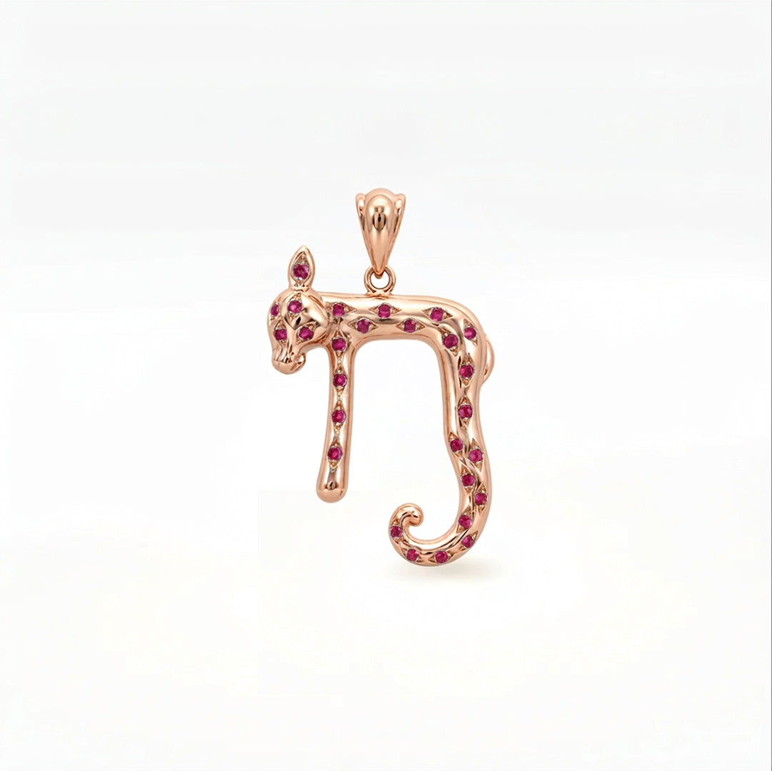A rose gold pendant shaped like the Hebrew letter Nun, embellished with small round red gemstones, shown on a clean white background.